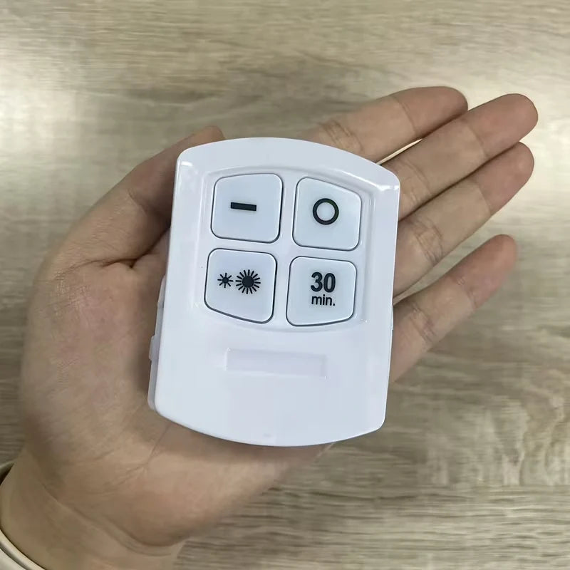 A hand holding a small white plastic remote control with four buttons, featuring a minus sign, circle, asterisk with burst symbol, and '30 min.' text, set against a light wood grain background.